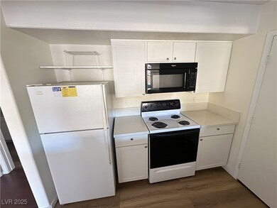 Kitchen featuring white cabinets, range with electric stovetop, and freestanding refrigerator