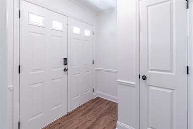 Foyer entrance with wood finished floors and ornamental molding