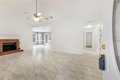 Unfurnished living room featuring ceiling fan, a fireplace, light marble finish flooring, lofted ceiling, and a chandelier