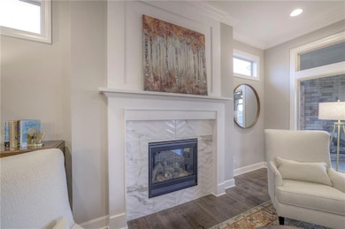 Sitting room featuring a tiled fireplace, hardwood / wood-style flooring, and crown molding
