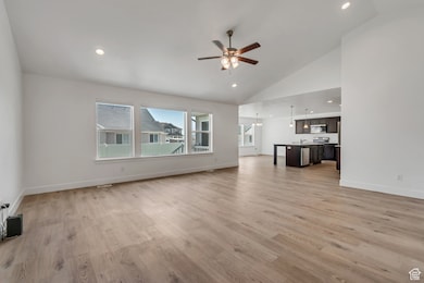 Unfurnished living room featuring recessed lighting, light wood finished floors, a ceiling fan, a chandelier, and high vaulted ceiling