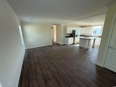 Unfurnished living room featuring crown molding, dark wood-style floors, a sink, baseboards, and recessed lighting