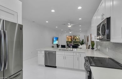 Kitchen with appliances with stainless steel finishes, backsplash, white cabinetry, a peninsula, and recessed lighting