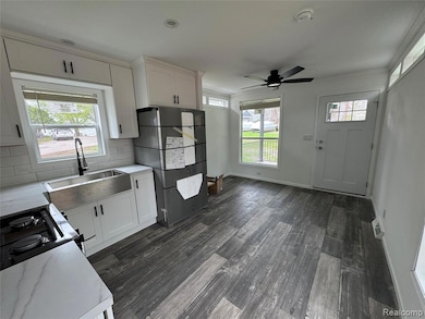 Kitchen with white cabinetry, backsplash, dark wood-style flooring, ceiling fan, and black gas range oven