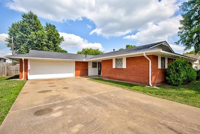 Ranch-style home with driveway, brick siding, an attached garage, and roof with shingles