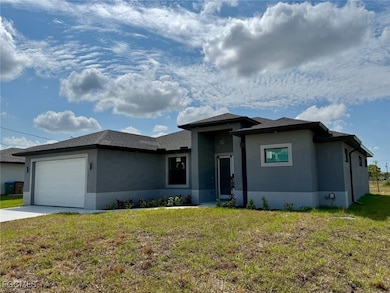Prairie-style house with stucco siding, an attached garage, a front yard, and driveway