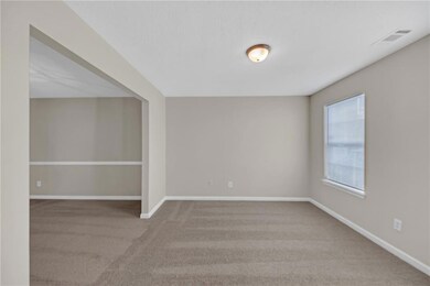Carpeted empty room with visible vents and baseboa