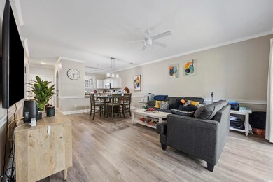 Living room with light wood-style floors, a ceiling fan, and crown molding