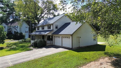 Traditional home with roof with shingles, a garage, concrete driveway, a front yard, and a porch
