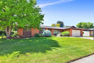 View of front of house with an attached garage, concrete driveway, a front lawn, and brick siding