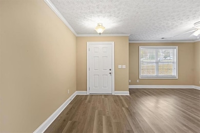 Entrance foyer with ornamental molding, wood finished floors, a textured ceiling, and a ceiling fan
