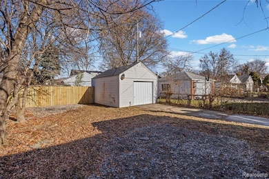 Fenced backyard featuring driveway, a shed, and a garage