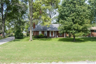 Ranch-style home with brick siding, a front yard, covered porch, and a chimney