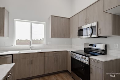 Kitchen featuring appliances with stainless steel finishes, dark wood-style flooring, and modern cabinets