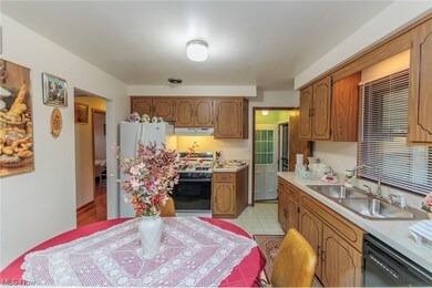 Kitchen with light tile flooring, dishwasher, sink, white refrigerator, and range