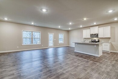 Kitchen with appliances with stainless steel finishes, open floor plan, dark wood-type flooring, recessed lighting, and white cabinets