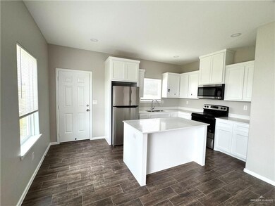 Kitchen featuring appliances with stainless steel finishes, a sink, white cabinets, a kitchen island, and recessed lighting
