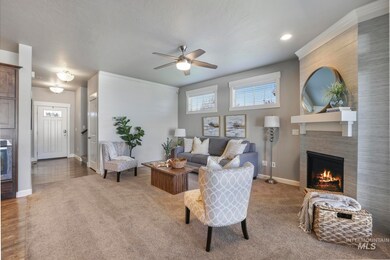 Carpeted living room with a lit fireplace and ceiling fan