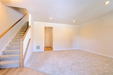 Empty room with recessed lighting, light carpet, visible vents, baseboards, and stairway