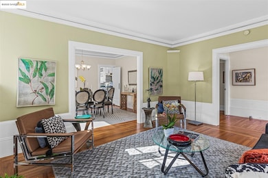 Living room featuring a chandelier, crown molding, wood finished floors, and wainscoting