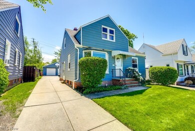 Bungalow featuring an outdoor structure, a garage, and a front lawn
