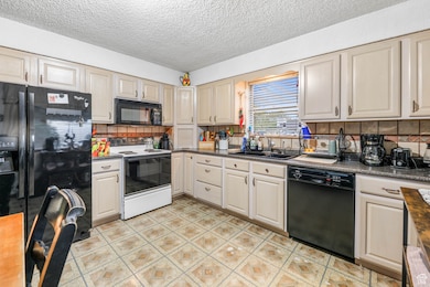 Kitchen with black appliances, a textured ceiling, and tasteful backsplash