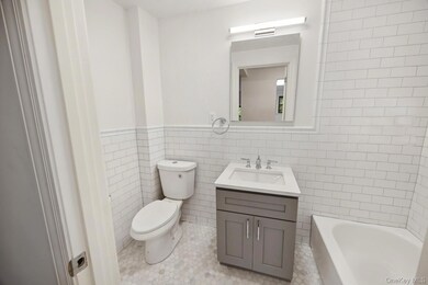 Bathroom featuring tile walls, vanity, light tile patterned floors, and a wainscoted wall