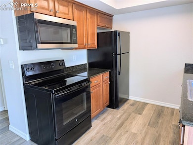 Kitchen with black appliances, light wood-type flooring, and brown cabinetry