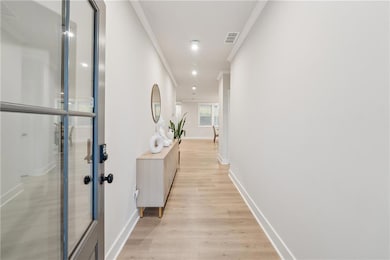 Hallway featuring crown molding, light wood-type flooring, and baseboards