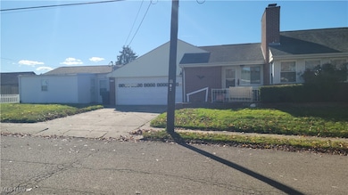 Single story home featuring concrete driveway, a front yard, a chimney, an attached garage, and brick siding