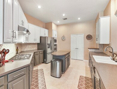 Spacious island kitchen with solid surface counter tops, tile back splash and extensive cabinetry ~