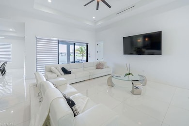 Tiled living room with ceiling fan, a tray ceiling, and recessed lighting