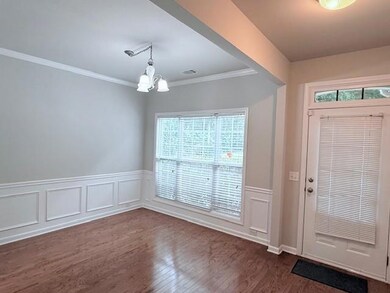 Entrance foyer featuring a chandelier, dark wood-style floors, crown molding, and a wainscoted wall