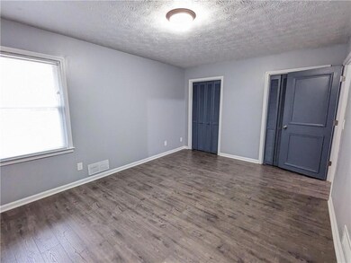 Unfurnished bedroom with multiple closets, dark wood-type flooring, and a textured ceiling