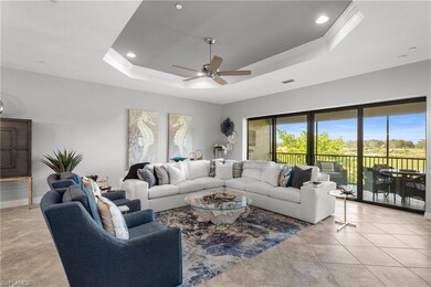 Living area featuring a tray ceiling, ceiling fan, light tile patterned floors, recessed lighting, and crown molding