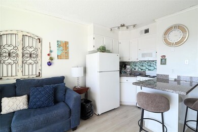 Kitchen with decorative backsplash, white appliances, white cabinets, a breakfast bar area, and a textured ceiling