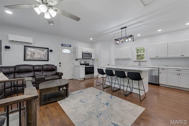 Living room with dark wood finished floors, recessed lighting, ceiling fan, and a wall unit AC