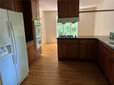 Kitchen featuring appliances with stainless steel finishes, under cabinet range hood, hardwood flooring, granite countertops, and ornamental molding