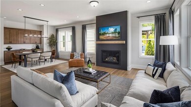 Living room over looking the dining room with light wood-style flooring, a fireplace, recessed lighting, plenty of natural light. Photos are of the Tallulah Model Home and are not representative of actual home. Designer features may vary.