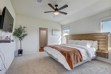Carpeted bedroom with ceiling fan and vaulted cei