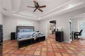 Tiled bedroom featuring baseboards and a raised ceiling