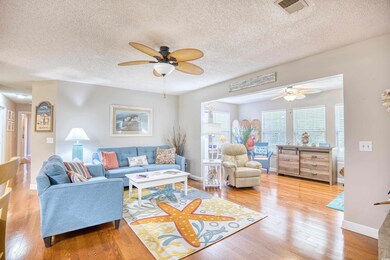 Living room with ceiling fan, a textured ceiling, 