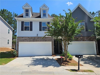 View of front of property featuring a garage, driveway, and brick siding