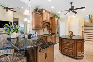 Kitchen featuring ceiling fan, appliances with stainless steel finishes, hanging light fixtures, and decorative backsplash
