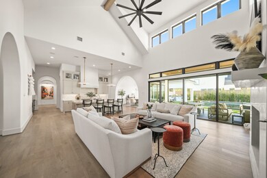 Another look at the main living space shows the incredible views out to the pool area. This space truly has a grand but cozy feel with details like venetian plaster fireplace and range hood. The hall leads to a beverage area and a second kitchen. On the other side is the formal dining area before you get to the gameroom.