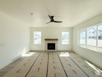 Unfurnished living room with a tiled fireplace, a textured ceiling, and ceiling fan
