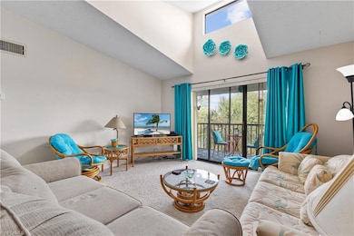 Carpeted living room with a high ceiling - only 3rd floor units offer a skylight
