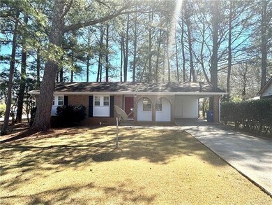 Single story home featuring brick siding, concrete driveway, and a carport