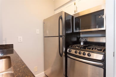 Kitchen featuring dark stone counters, appliances