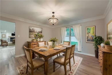 Dining area featuring crown molding, light wood finished floors, a fireplace, and a chandelier